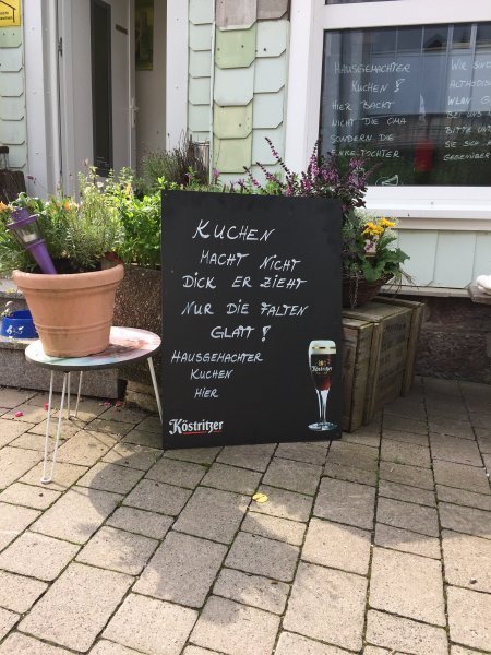 Tafel mit lustigem Spruch zum Thema Kuchen vor dem Café in Oberhof